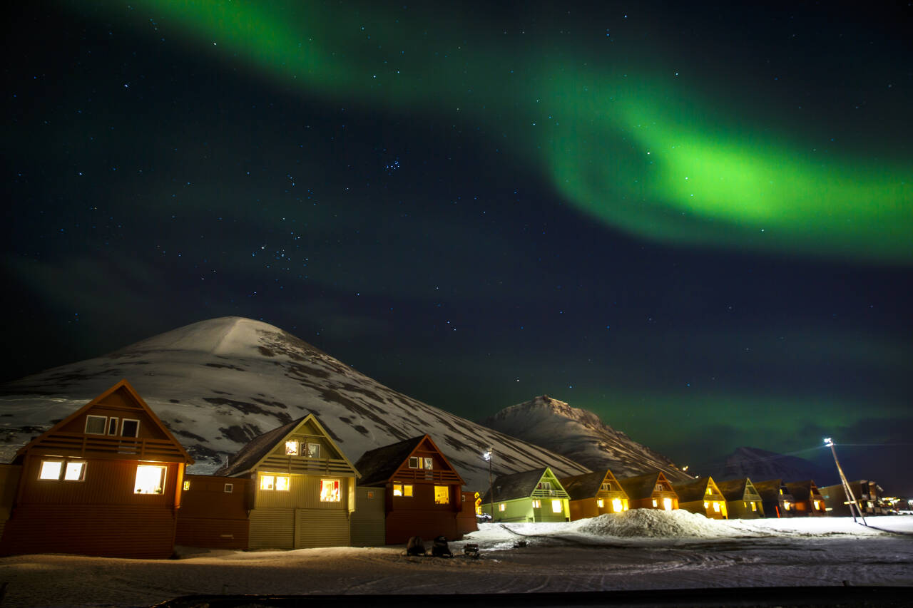 Hurtigruten og Store Norske inngår en 30 år lang samarbeidsavtale om utvikling av reiselivet på Svalbard, opplyser Hurtigruten i en pressemelding. Her nordlys over spisshusene i Longyearbyen. Arkivfoto: Heiko Junge / NTB