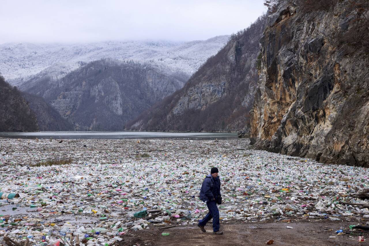 En mann passerer et stort flak med søppel elva Drina i Bosnia. Mengden søppel som produseres i verden, ventes å øke kraftig de neste tiårene. Foto: Armin Durgut / AP / NTB
